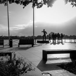 Silhouette people by swimming pool against sky