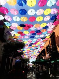 Low angle view of multi colored umbrellas hanging on building