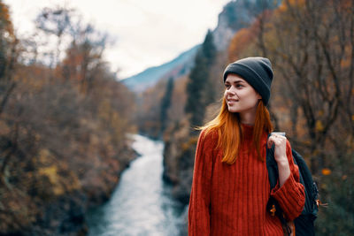 Young woman looking away while standing on tree during winter