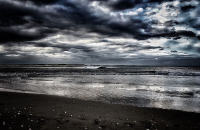 Scenic view of beach against cloudy sky