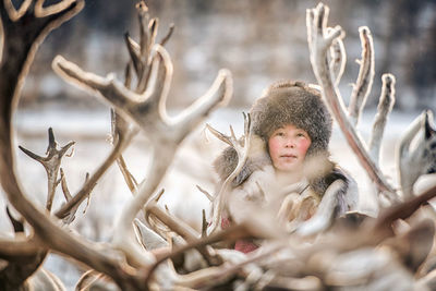 Mid adult woman standing by deer in forest during winter