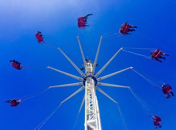 Low angle view of swing ride against clear blue sky