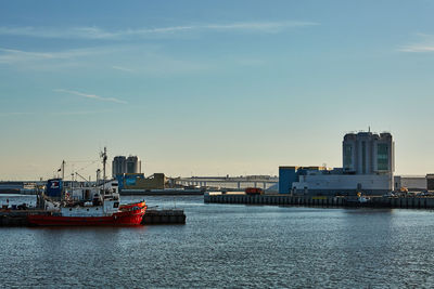 Boats moored at harbor against sky in city