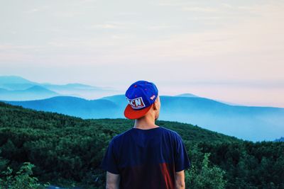 Rear view of man standing on landscape against sky