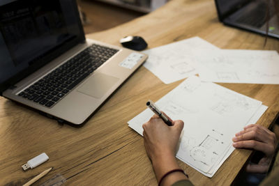 Female carpenter making design on paper at desk in industry