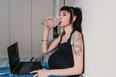 Young woman using mobile phone while sitting at home