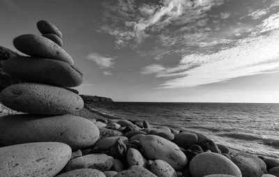 Stack of pebbles on beach against sky
