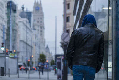 Rear view of man walking on street in city