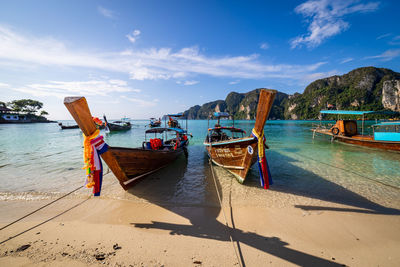 Boats moored on beach against sky