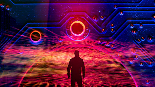 Rear view of silhouette man standing against illuminated multi colored lights