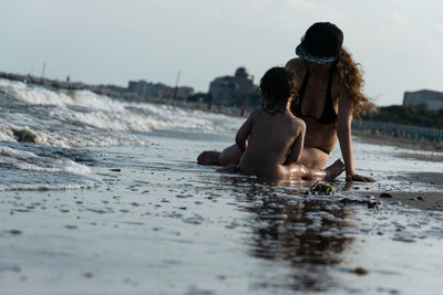 Mother sitting with child on shore at beach