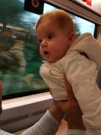 Baby girl looking through window while traveling in train