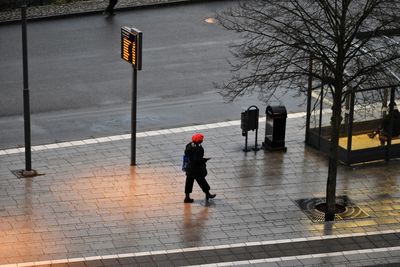 Rear view of woman walking on footpath in city