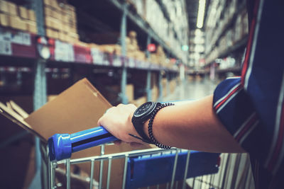 Midsection of woman holding shopping cart in warehouse