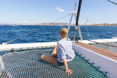 Rear view of senior woman sailing on sea against sky