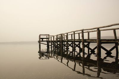 Silhouette pier over sea against clear sky