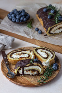 Sponge cake roll with chocolate and cream cheese with glaze and blueberry. biscuit swiss roll. 