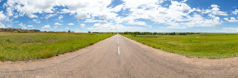 Road amidst field against sky