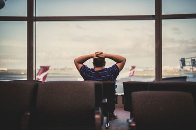 Young man sitting at airport against sky