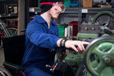 Male worker repairing machinery in workshop