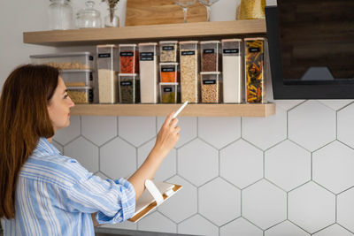 Smiling woman looking at spices at kitchen
