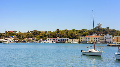 Sailboats in sea against buildings in city