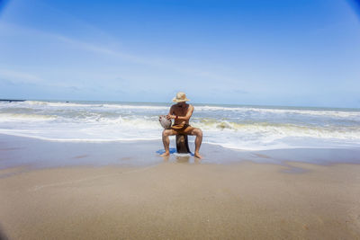 Rear view of boy on beach against sky