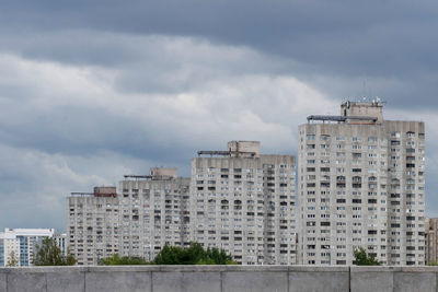 Under the expressive dark sky, covered with rain clouds, a block of high-rise residential buildings.