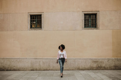 Full length of woman standing against building in city