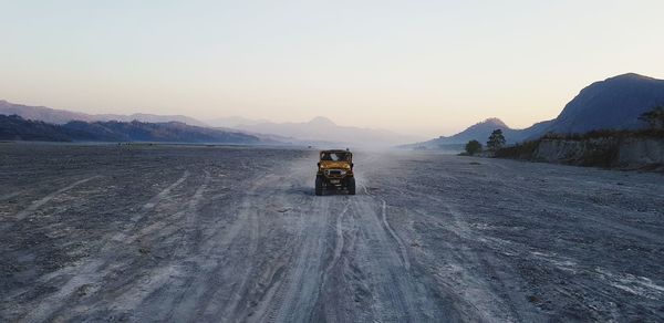 Road by snowcapped mountains against clear sky