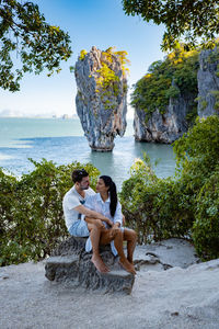 Young man sitting on rock by sea