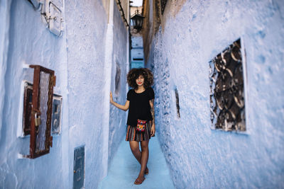 Full length portrait of woman standing against wall