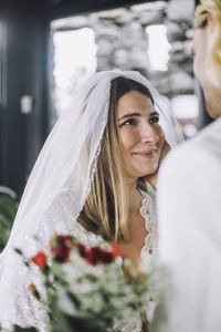 Smiling mid adult bride in wedding dress looking at groom