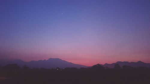 Scenic view of silhouette mountains against clear sky at night