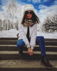 Portrait of woman sitting on snow covered tree