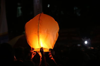 Cropped hands holding illuminated paper lantern at night