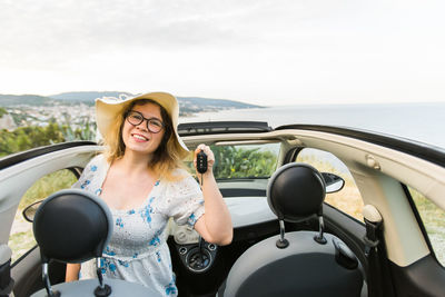 Portrait of young woman wearing sunglasses while sitting in car