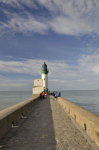 Lighthouse on beach against sky