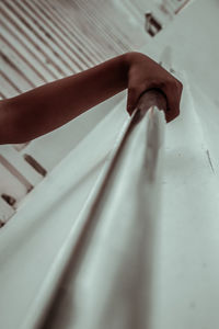 Close-up of hand on railing against wall