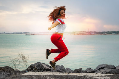 Full length of woman on beach against sky during sunset