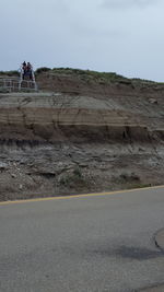 People on road by mountain against sky