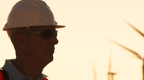 Side view of man wearing hat against orange sky