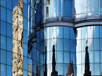 Low angle view of glass building against blue sky