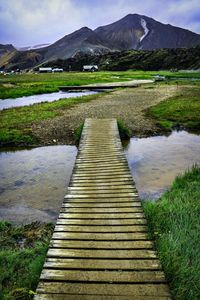 Footpath by lake against sky