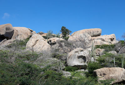 Rocks on landscape against clear blue sky