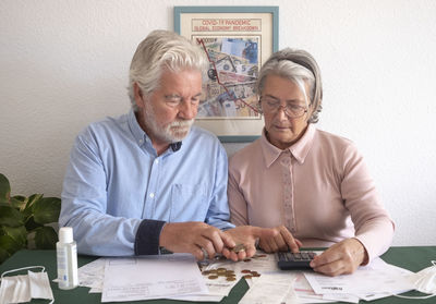 Senior couple counting money on table at home