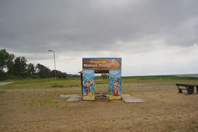 Road sign on field against sky