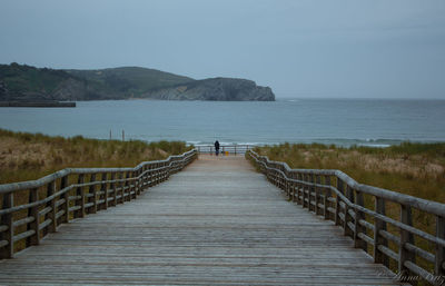 Boardwalk over lake against sky