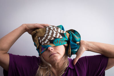 Close-up of woman with head wrapped in scarf against white background