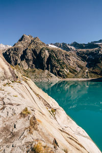 Scenic view of lake and mountains against clear blue sky